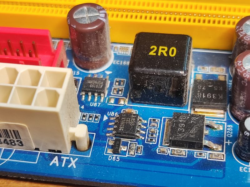 Electronic Components on a Motherboard Close-up of a motherboard with visible MOSFET transistors and other elements.