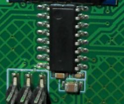 Close-up of an integrated circuit on a green PCB with various components and traces.