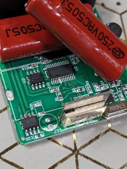 Close-up of a circuit board with various electronic components, including large red capacitors and an unidentified chip.