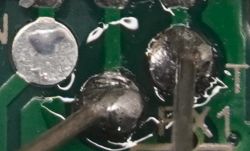 Close-up of solder points and traces on a circuit board with TX and RX markings visible.