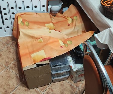 Pudła i przedmioty przykryte kocem na podłodze.
