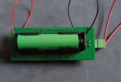 Płytka PCB z uchwytem na ogniwo 18650 i zielonym złączem zaciskowym, podłączone przewody