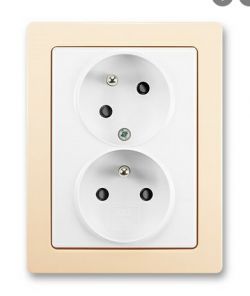 Double electrical socket with grounding on a beige frame.