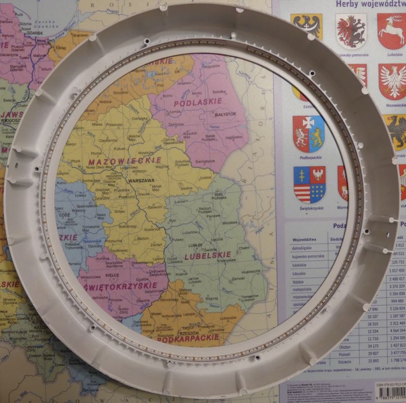 Okrągła rama z pierścieniem LED leży na mapie Polski z widocznymi nazwami województw