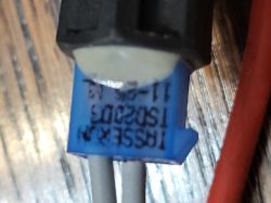 Zbliżenie niebieskiego elementu elektronicznego z nadrukiem, między metalowymi powierzchniami