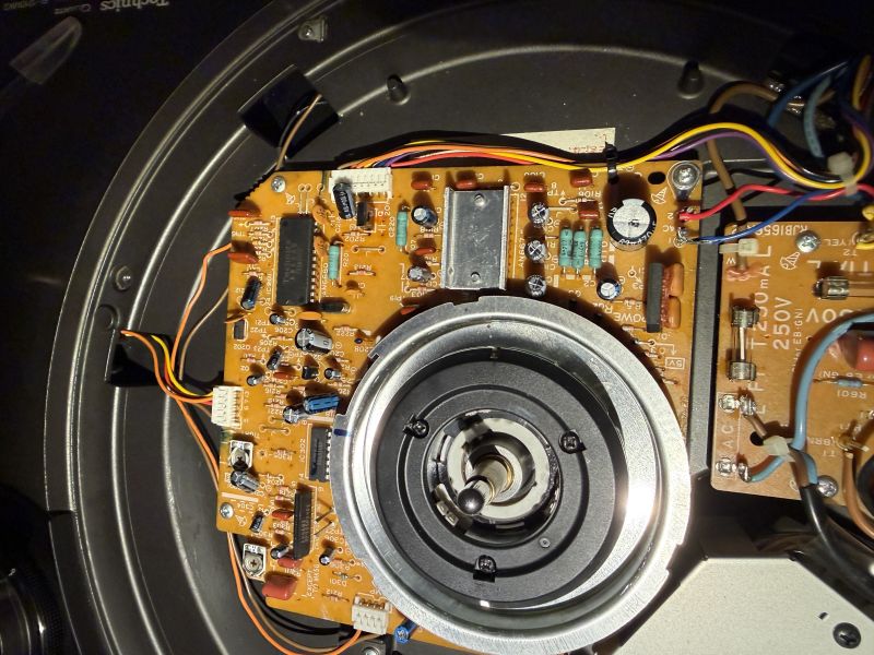 Wnętrze urządzenia audio: płytka elektroniczna z przewodami i centralny mechanizm talerza