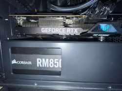 Karta graficzna GeForce RTX wewnątrz obudowy komputera, nad zasilaczem Corsair RM850.