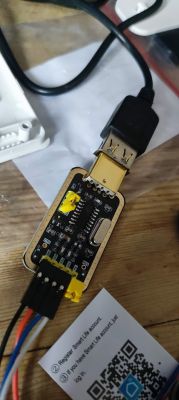 USB-Serial adapter connected to wires on a wooden table.
