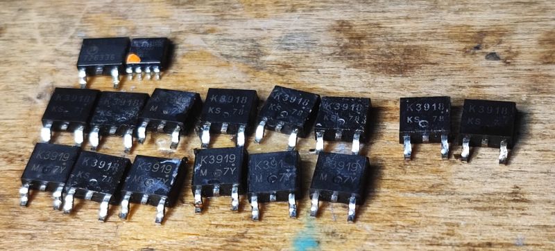 Desoldered MOSFET Transistors from Motherboard A set of desoldered MOSFET transistors from a motherboard on a wooden table.