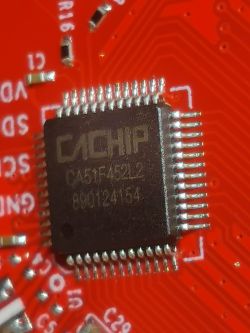 Close-up of a CACHiP chip on a red circuit board.