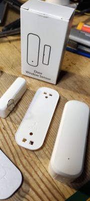 Door/Window Sensor with Packaging Door/window sensor with packaging and casing on a wooden surface