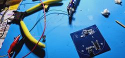 Electronic tools and circuit board on a blue workbench.