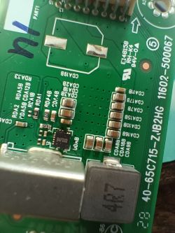 Zbliżenie na zieloną płytkę drukowaną z różnymi komponentami elektronicznymi i oznaczeniami.
