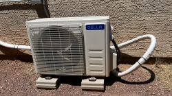 Della Mini Split Outdoor Unit Beside Building Outdoor unit of a Della mini split air conditioner placed on concrete blocks next to a building wall.