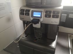 Ekspres do kawy Saeco Aulika na blacie kuchennym, z kubkiem pod wylewką i wężem po lewej stronie