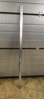 Long metal pipe standing upright in front of a gray garage door.