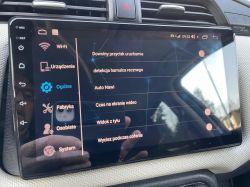 Ekran dotykowy w samochodzie z widokiem menu ustawień, pokazujący opcje takie jak Wi-Fi, Urządzenie, Ogólne, Fabryka, Osobiste i System.