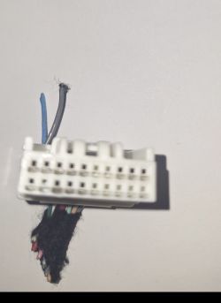 Biała kostka elektryczna z metalowymi pinami i kolorowymi przewodami