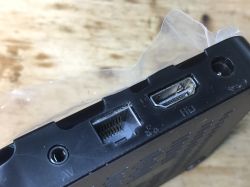 Zbliżenie na złącza TV boxa: AV, Ethernet i HDMI, na tle drewnianym.