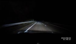 Zdjęcie nocnej jazdy samochodem z włączonymi światłami drogowymi.