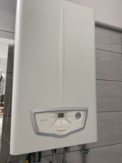 Gazowy piec Immergas w łazience na ścianie z wyświetlaczem pokazującym 59 stopni.