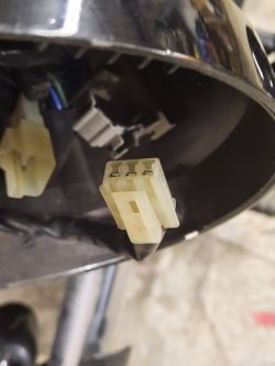 Zbliżenie na plastikową wtyczkę w reflektorze motocykla.