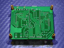 Bottom view of a green PCB with through-hole pads, traces, and mounting holes