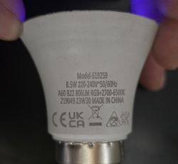 Close-up of an LED bulb label showing specs: 8.5W, 220–240V, 806 lm, RGB, 2700–6500K