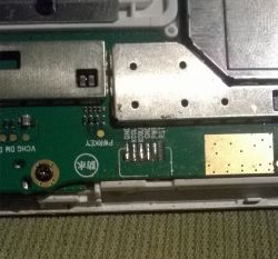 Zdjęcie zbliżeniowe płyty głównej z widocznymi pinami i złączem na urządzeniu elektronicznym.