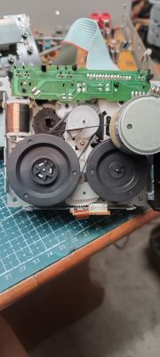 Wnętrze mechanizmu magnetofonu kasetowego z kołami zamachowymi, paskami i płytką PCB