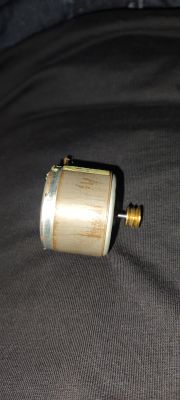 Mały silnik elektryczny z przekładnią ślimakową, leżący na ciemnym materiale