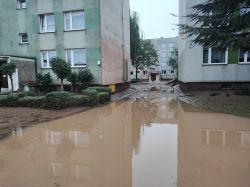 Zalany teren pomiędzy blokami mieszkalnymi po powodzi.