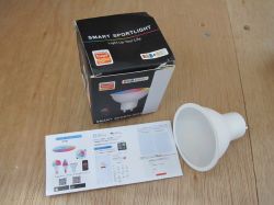 Smart RGB Bulb with Packaging and Instructions Smart spotlight bulb next to packaging and instructions.