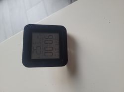 Electronic clock with thermometer on a white surface.
