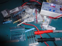 Close-up of a workspace with electronic components and a multimeter on a blue workbench.