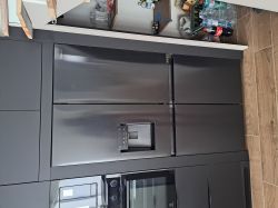 Czarna lodówka do zabudowy z frontami zlicowanymi z meblami kuchennymi