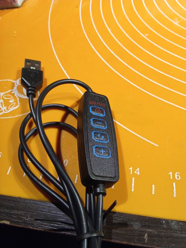 Pilot z przewodem USB na pomarańczowej macie.