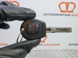 Metalowy kluczyk samochodowy z pilotem, trzymany w rękawiczce ochronnej.