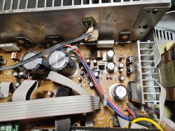 Wnętrze urządzenia elektronicznego z widocznymi kondensatorami, tranzystorami i przewodami połączeniowymi.