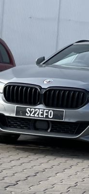 Srebrny samochód marki BMW na parkingu, z widoczną tablicą rejestracyjną S22EFO.