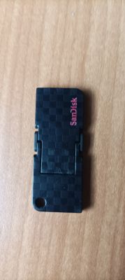 Czarny pendrive SanDisk 16 GB na drewnianej powierzchni.