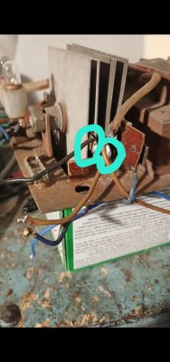 Zbliżenie na elementy elektryczne z radiatorem i przewodami, dwa miejsca zaznaczone turkusowym kółkiem.