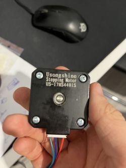 Stepper motor Usongshine trzymany w ręce, czarnego koloru z przewodami.