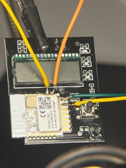 Close-up of a PCB with yellow, orange, and green wires connected.