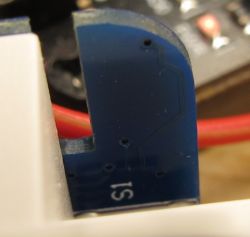 Close-up of a section of a circuit board with the S1 marking and a red wire in the background.