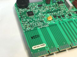 Zbliżenie na fragment zielonej płytki drukowanej programatora zmywarki z elementami elektronicznymi SMD oraz oznaczeniami.