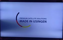 Zaciemniony ekran telewizora z napisem PREMIUM SATELLITE SOLUTIONS MADE IN USINGEN.