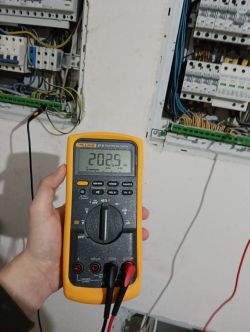 Multimetr Fluke 87V wskazuje pomiar 202,5 w skrzynce elektrycznej.