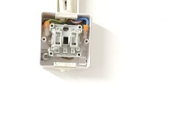 Zbliżenie na wnętrze puszki elektrycznej z gniazdem włącznika światła.