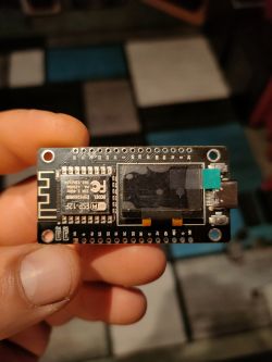 NodeMCU ESP8266 development board with a small built-in OLED display, held in a hand
